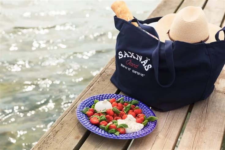 En närbild av en korg fylld med olika bär och frukter, symboliserar de naturliga livsmedel och lokala specialiteter som kan upptäckas på Saxnäs Camping.