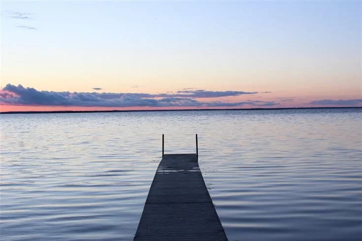 Bild av en vacker horisont vid Saxnäs Camping med ett spegelblankt, blått vatten som breder ut sig under en klar himmel, vilket skapar ett lugnt och inbjudande landskap.