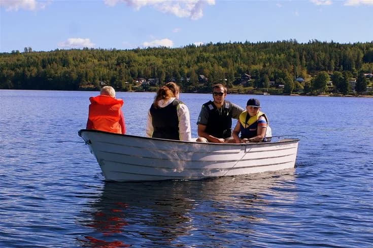 En lugn sjö med en båt som ligger förtöjd vid strandkanten, omgivet av grönskande natur. Idealisk för rekreation och båtliv.