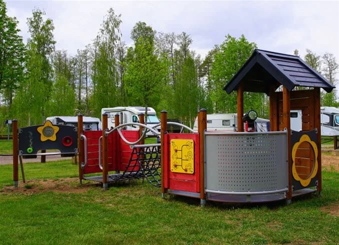 En lekplats och grönområde på Otterbergets bad och camping, med utomhuslekutrustning och öppna ytor för rekreation.