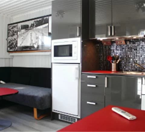 Bild på ett modernt kök med ljusa väggar, ett rymligt golv och flera hushållsapparater, inklusive kyl, spis och mikrovågsugn. Köket är en del av Gustavsvik Resorts boendefaciliteter.