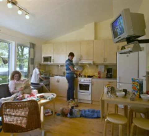 Bild av ett modernt kök och vardagsrum på Gustavsvik Resort. Rummet har snygg inredning med en stor köksö, stilrena vitvaror, och bekväma sittplatser. Golvet är i trä och taket är ljust, vilket ger en luftig känsla.