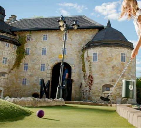 En bild av Gustavsvik Resort med en vacker slottsliknande byggnad i bakgrunden och en golfbana i förgrunden.