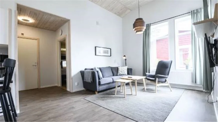 Ett interiörfoto från Östersunds Camping, som visar ett ljust och modernt vardagsrum med trägolv, träinredning och bekväma möbler. Rummet har ett högt tak och en välkomnande atmosfär.