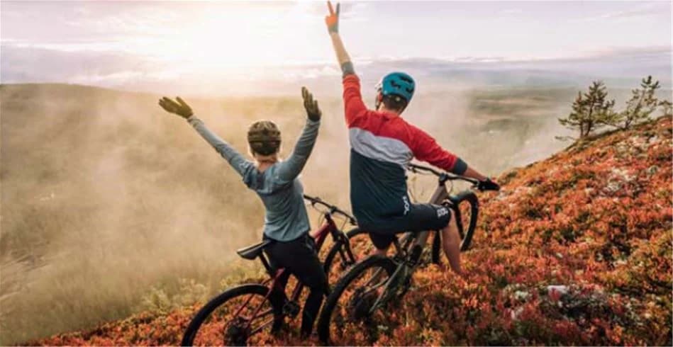 En cykel parkerad på en campingplats vid Idre Fjäll med synlig cykelram, hjul och styre. Bakgrunden visar barrskog och campingutrustning, vilket skapar en känsla av friluftsliv och rekreation.