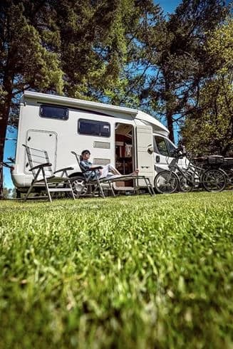 En bild på Björknäs camping med husvagnar och husbilar uppställda på en campingplats omgiven av grönska.