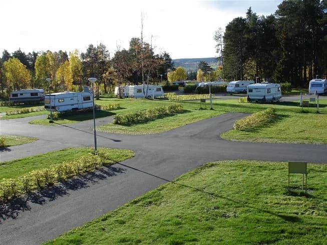 En campingplats i Östersund med gräsmattor, parkerade husbilar och trädgårdsanläggning.