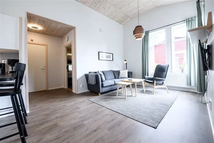 Ett modernt och ljust inrett rum på Östersunds camping med trädetaljer, välkomnande möbler och mjuk belysning. Golvet är av trä och harmoniserar med rummets naturliga färgschema.