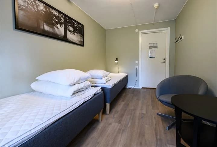 Ett välkomnande sovrum på Östersunds camping med en bäddad säng, inredning med ljust golv och tak, samt en praktisk och enkel design.