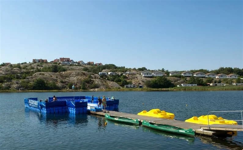 En båt glider fram på en glittrande sjö omgiven av natursköna landskap vid Wiggersviks camping.