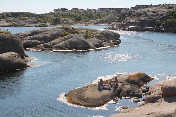 Bild av Wiggersviks camping med en vy över en vattenresurs, där en vattendrag rinner längs en kustlinje med stenar och vegeterade stränder.