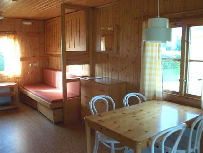 Interiörbild av ett campingområde i Vadstena med träinredning; rummet har trägolv, trätak och trämöbler, vilket skapar en varm och inbjudande atmosfär.