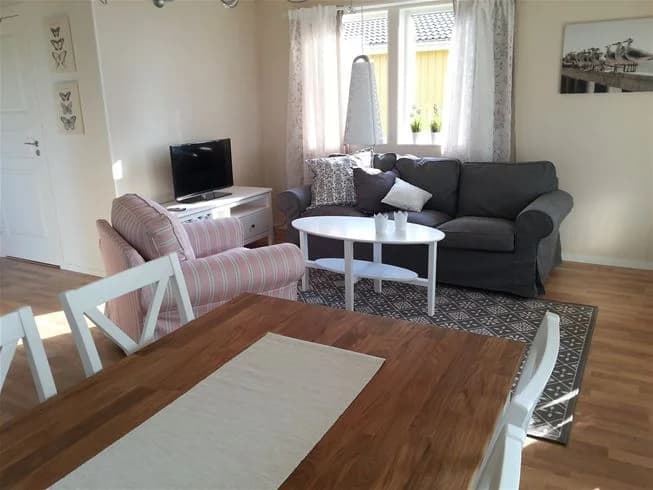 En mysig stuga på Vadstena camping med trägolv, en bekväm soffa och ett träbord, inrett i en hemtrevlig och stilren design.