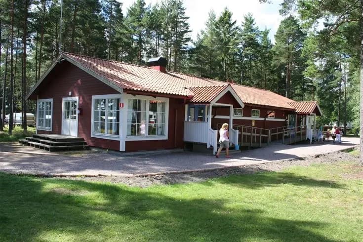 En mysig stuga med veranda omgiven av grönska, belägen på Strandstuvikens Havsbad & Camping, inbjuder till avkopplande stunder i solskenet.