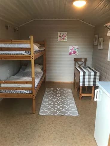 En mysig sovstuga på Strandstuvikens Havsbad & Camping med trägolv och träinredning, ett sovrum med en säng och en dörr.