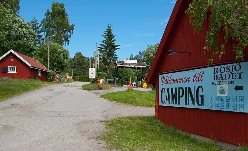 En grönskande campingplats med träd och gräsmattor, där det finns stugor och tält uppställda. Perfekt för utomhusaktiviteter och avkoppling i naturen.