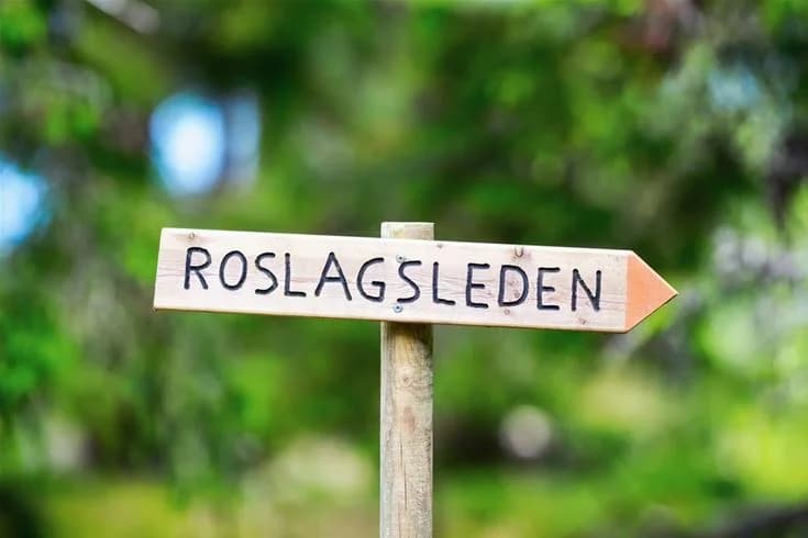 En skylt vid infarten till Norrtälje camping omgiven av grönskande växter.
