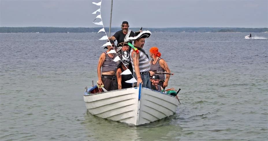 En båt seglar på en lugn sjö vid Norje Boke Camping, omgiven av grönskande skogar. Perfekt för rekreation och avkoppling.