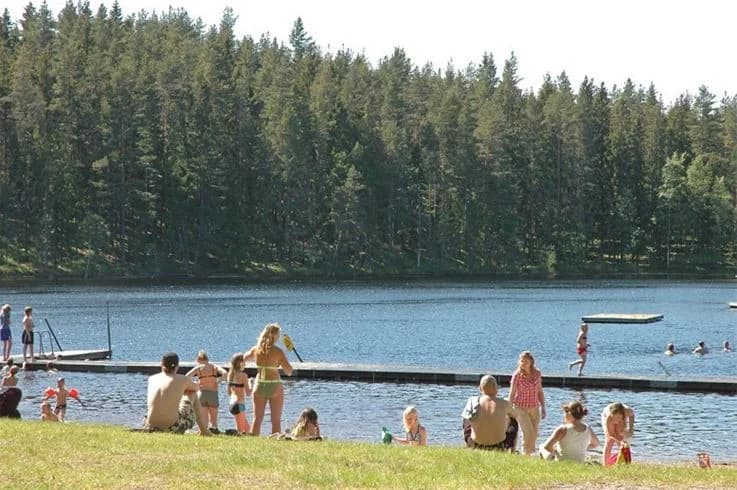 En avkopplande vy över en campingområde vid en sjö, med rekreationsmöjligheter och utemöbler för besökare att njuta av semestern vid vattnet.