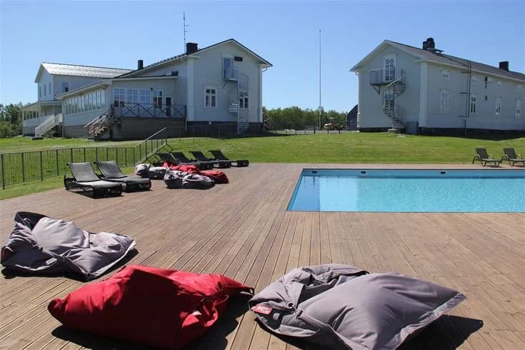 En utomhuspool på Cape East med solsängar och parasoller, omgiven av grönska, perfekt för avkoppling och rekreation.