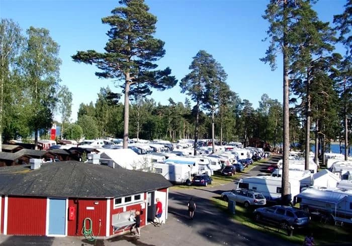 En översikt av Karlsborgs camping med campingplatser, parkeringsplatser och omgivande grönska, belägen i en semesterort.