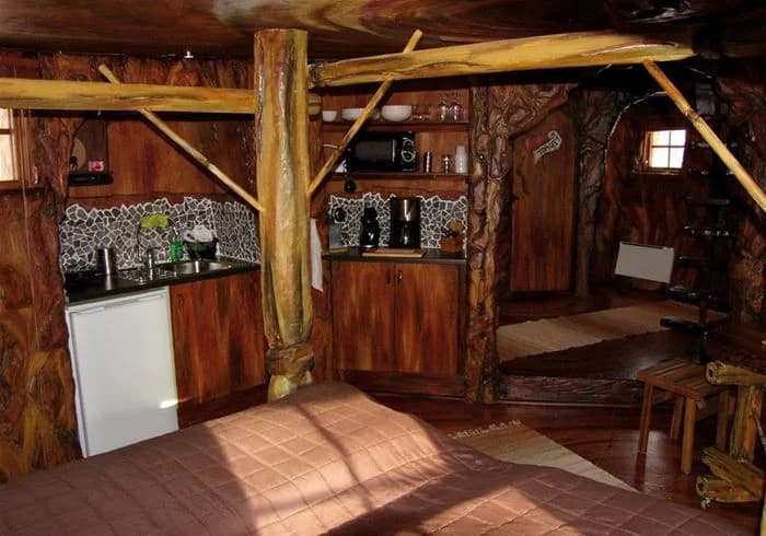 Interiör av en stuga med träinredning på Karlsborgs camping, inklusive takbjälkar och träplankor som ger en rustik känsla.