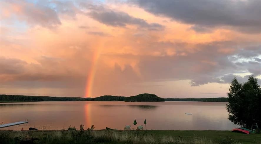 En vacker, naturlig scen vid Sagaliden, där en regnbåge sträcker sig över en kvällshimmel med moln. Natur och horisont skapar ett stämningsfullt och fridfullt landskap i skymningen.