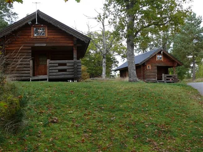 En pittoresk stuga med träfasad och snedtak, omgiven av grönskande natur i Grännäs camping och stugby.