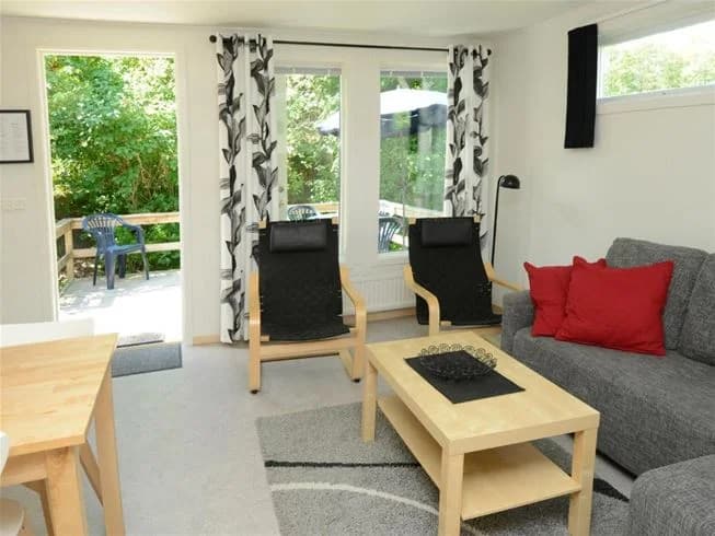 Ett ljust och inbjudande vardagsrum på Gullbrannagården med trägolv, bekväma sittplatser och modern belysning.