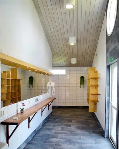 En inbjudande och varm inomhusmiljö på Gullbrannagården. Välvd träinredning i tak och väggar, ljusa golv av trä eller kakel, samt stilfulla belysningsarmaturer som sprider mjukt ljus i rummet.