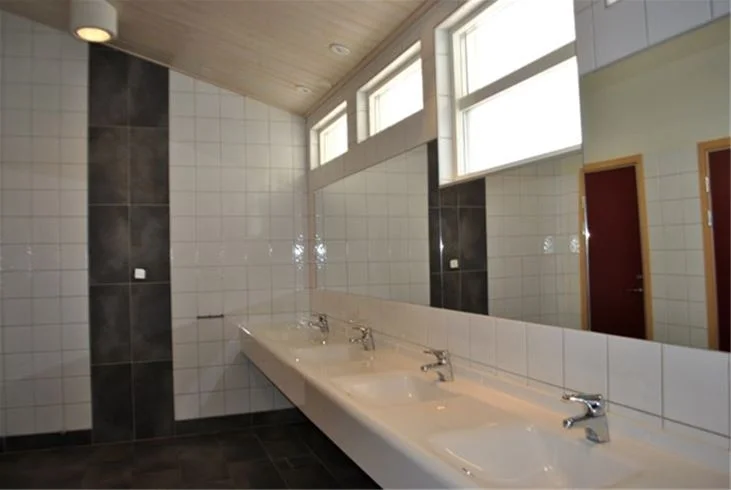 Ett badrum med en trävägg, golv och tak, en modernt designad badrumsinredning med ett handfat och tillhörande VVS-armaturer.