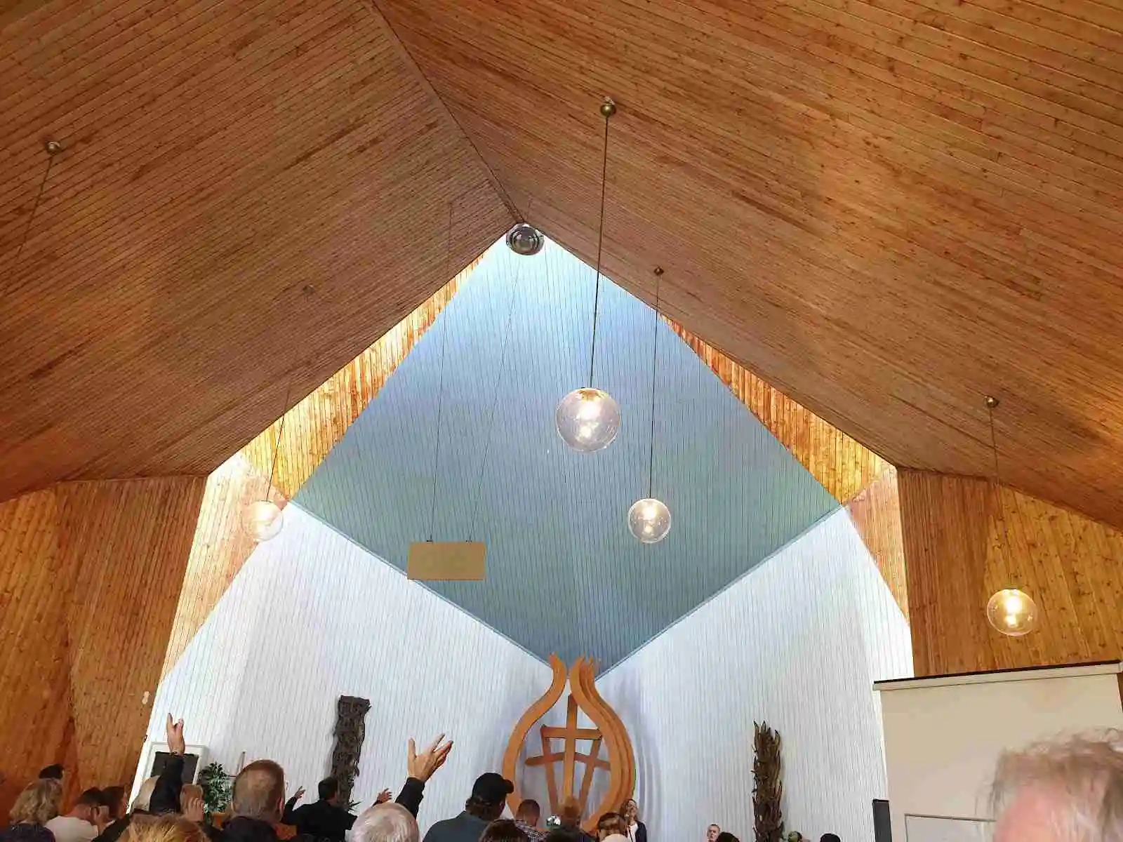 Interiör av ett kapell med trekantigt tak och religiösa föremål, belyst av mjukt ljus som skapar en fridfull atmosfär för andakt och reflektion.