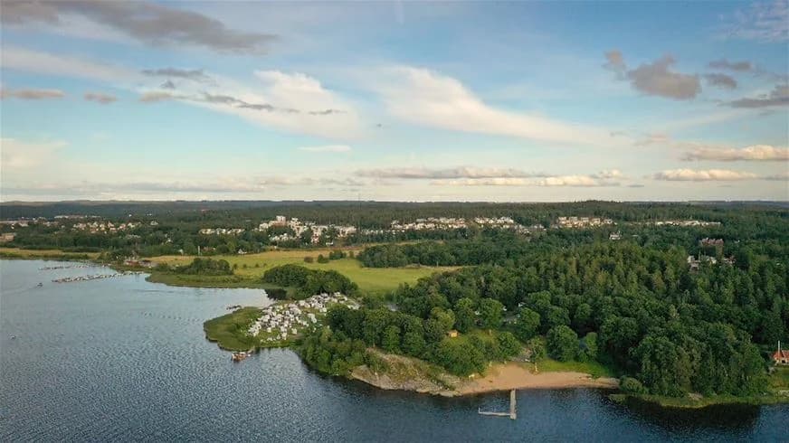 En flygvy över lövekulle camping med en stor sjö och omgivande grönska, där vattenresurser och kustnära landskap framträder tydligt.