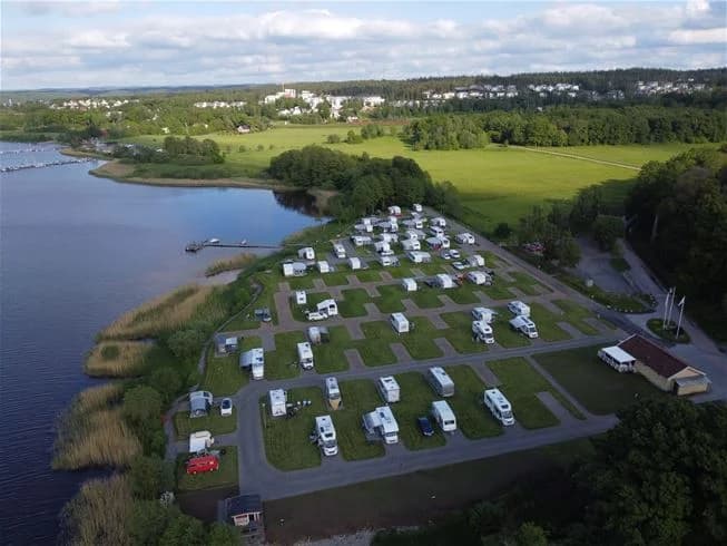 Fågelperspektiv över Lövekulle Camping med en vacker vy av ett vattenområde, omgiven av naturlandskap och vattenvägar.
