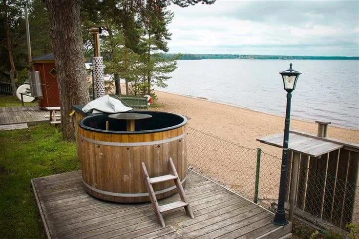 En träveranda med utemöbler och en bubbelpool vid Årsunda Strandbad.