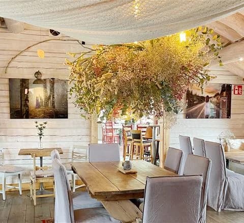 Interiörbild från Torsby camping som visar ett rum med trämöbler, inklusive stolar och matbord. Golvet är av trä och taket har ljusarmaturer som bidrar till en hemtrevlig atmosfär.