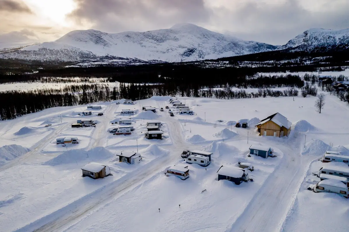 En snötäckt bergssluttning i vintrigt landskap vid Camp Kittelfjäll, med glaciärformationer och bergskedjor i bakgrunden.