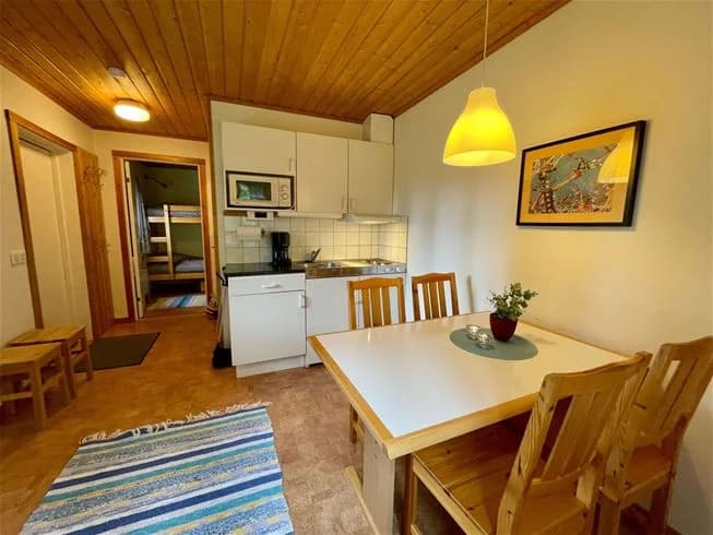 En interiör av en mysig stuga på Norråkers camping, med trämöbler och träpaneler som skapar en varm atmosfär. Rummet har trägolv och ett träbord i fokus, omgiven av ljusa träväggar och ett trätak.