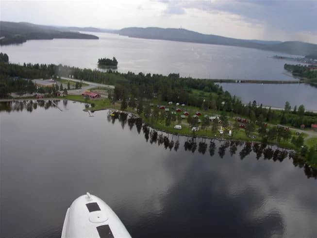 En stillsam och naturskön landskapsvy vid Camp Viking, med lugnt vatten som sträcker sig över kanalen, omgiven av grönskande skogar och kullar.