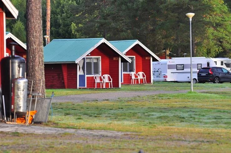 En grönskande rekreationsplats på Camp Viking, med vidsträckt gräsmatta, skuggande träd och ett mindre skjul.