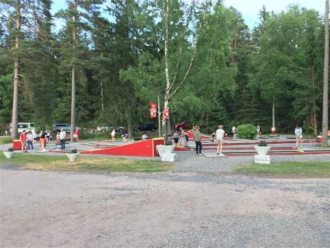 En lummig campingplats med tallar, en stig och lekutrustning för barn. Perfekt för utomhusaktiviteter och avkoppling.