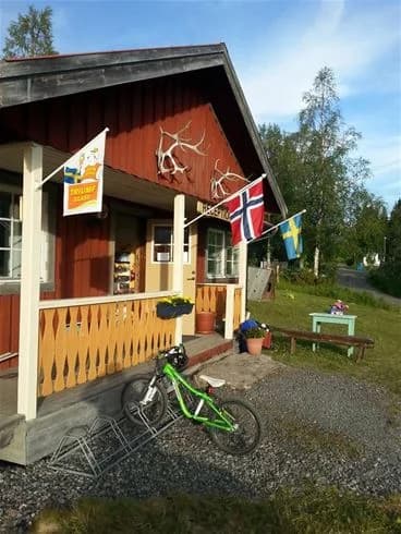 En campingstuga med dörr och träfasad, omgiven av en gräsmatta på Åre Camping.