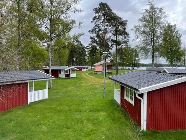 En lantlig stuga omgiven av grönskande träd och gräs på Gökaskratts camping.