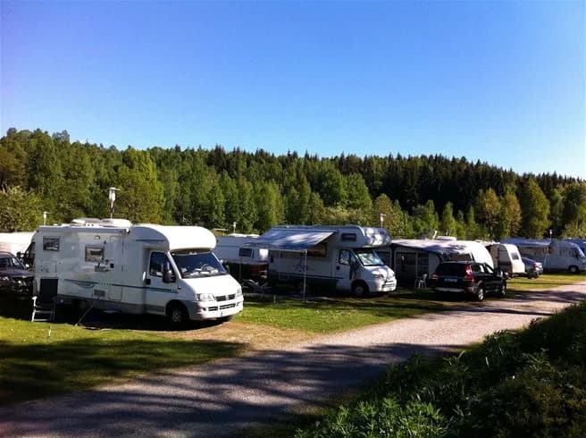 En husvagn och bil parkerade på grönskande campingplats vid Skotteksgården Camping & Stugby.