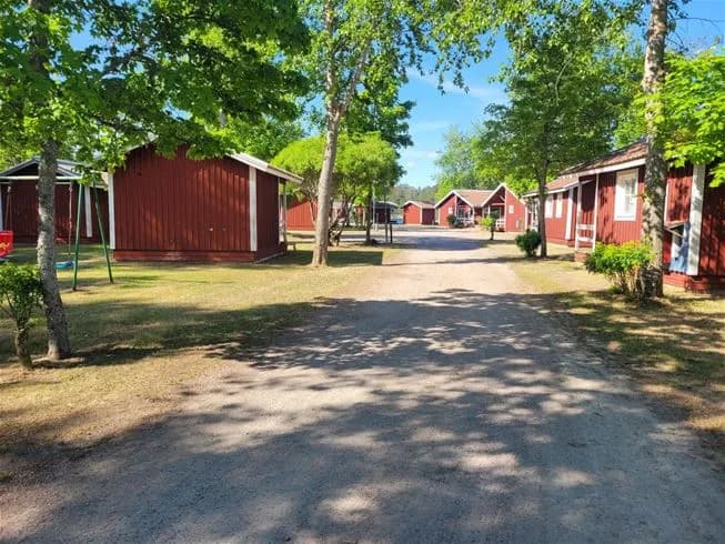 En mysig campingplats i Älvkarleby med en stuga omgiven av grönskande träd. Idyllisk och lugn miljö med en uppfart och skuggiga trädgårdsområden som skapar en inbjudande atmosfär.