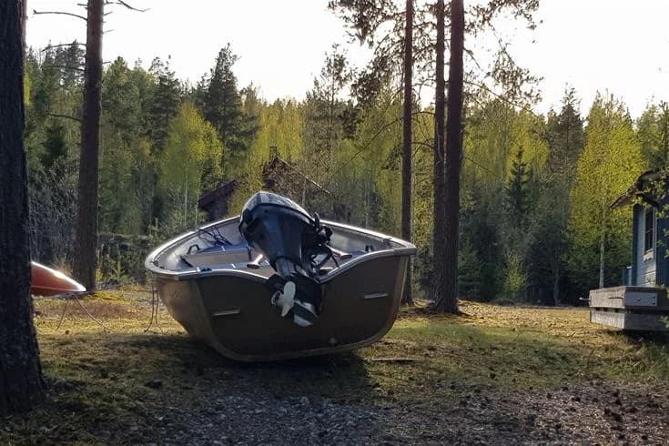 En bild av Ammeråns fiskecamp med flera motorbåtar och småbåtar förtöjda vid vattnet, omgivna av naturskön miljö. Perfekt för rekreation och fiskeäventyr.