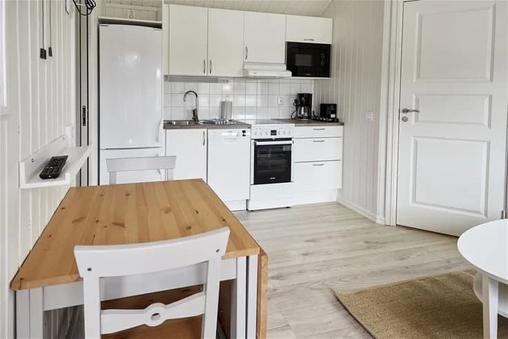 En mysig inomhusbild från Lagunen Camping & Stugor med trägolv och träinredning. Köket är utrustat med moderna skåp och en bänk som förstärker den varma och hemtrevliga atmosfären.