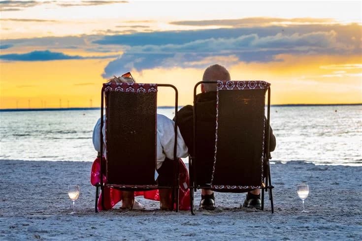En solig sommardag vid Gröndals camping & stugor med utemöbler på stranden. Besökare sitter och njuter av fritiden nära havet.