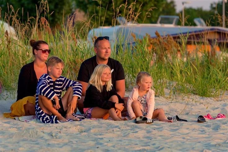 En familj njuter av sommaren på Gröndals camping & stugor. Barn leker glatt utomhus i den soliga miljön, vilket skapar en känsla av glädje och avkoppling under semestern.