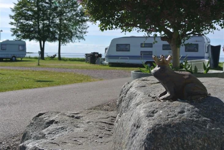 En campingplats med flera husvagnar och husbilar uppställda, omgiven av grönska.